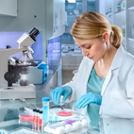 A woman looking at a cell specimen in a lab